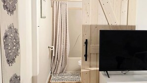 A modern interior with a sliding barn door, a flat-screen TV, and a patterned rug in a hallway. - Southern Charm Under the Oaks - Pet Friendly (Ocean Springs)