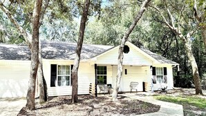A single-story house with a garage, surrounded by trees and a concrete driveway. - Southern Charm Under the Oaks - Pet Friendly (Ocean Springs)