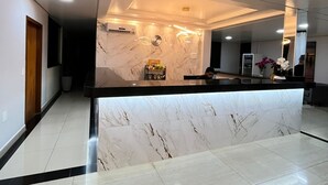 Un'accogliente area reception moderna, con un bancone in marmo, illuminazione a incasso e un design pulito e minimalista.