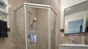 A bathroom with a glass-enclosed shower, a white toilet, a vanity with a mirror, and a bath mat. - Ravenwood (Niagara-on-the-Lake)