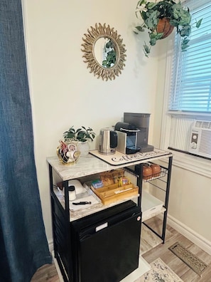 A kitchen area with a coffee station, a microwave, and a small refrigerator. - Ravenwood (Niagara-on-the-Lake)