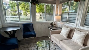 A sunroom with a sofa, a chair, a glass coffee table, and a small table with a lamp. - Ravenwood (Niagara-on-the-Lake)