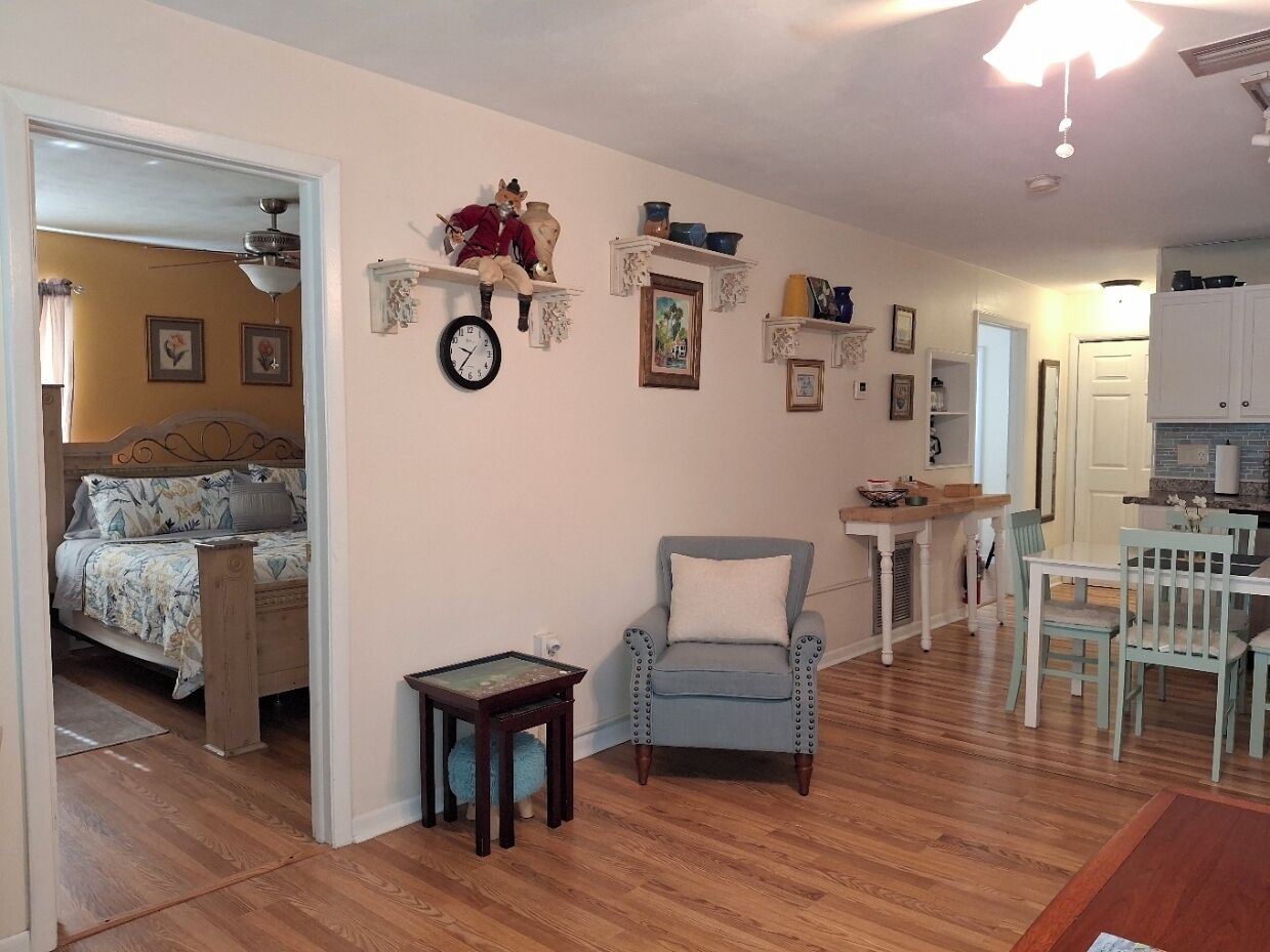 A cozy room with a bed, a small table, a chair, and a dining area with a table and chairs.