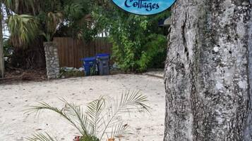 Cartell de benvinguda per a 'The Three Sisters Cottages', amb un arbre i una jardiniera amb flors grogues.