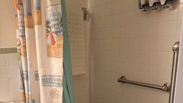 Un baño con ducha, inodoro y un perchero con botellas.