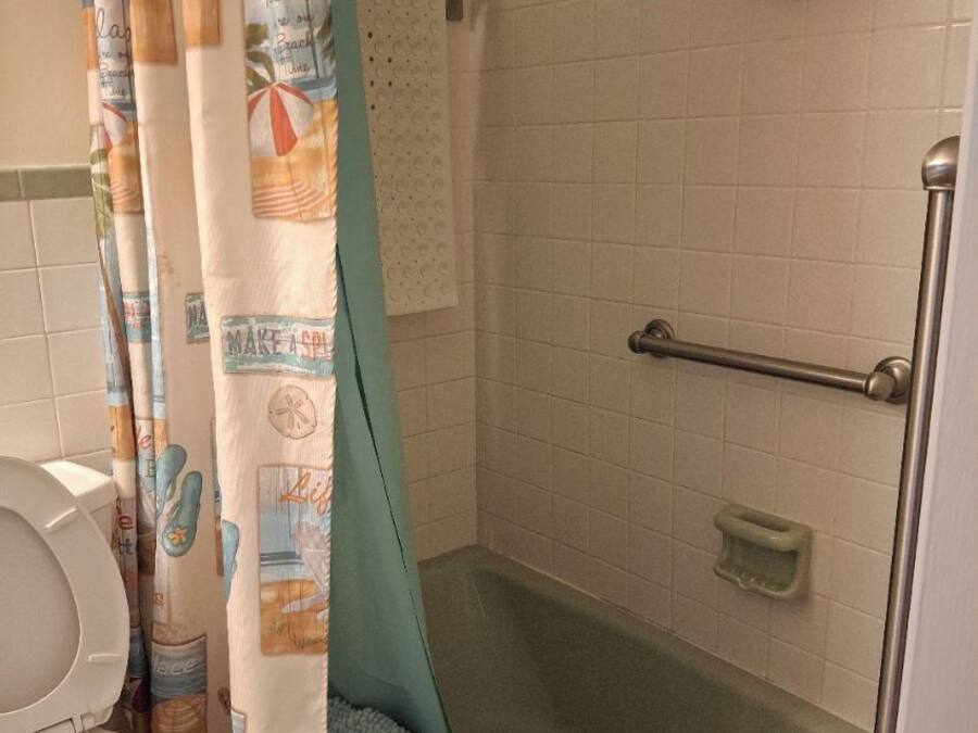 Ein Badezimmer mit Dusche, Toilette und Handtuchhalter mit Flaschen.