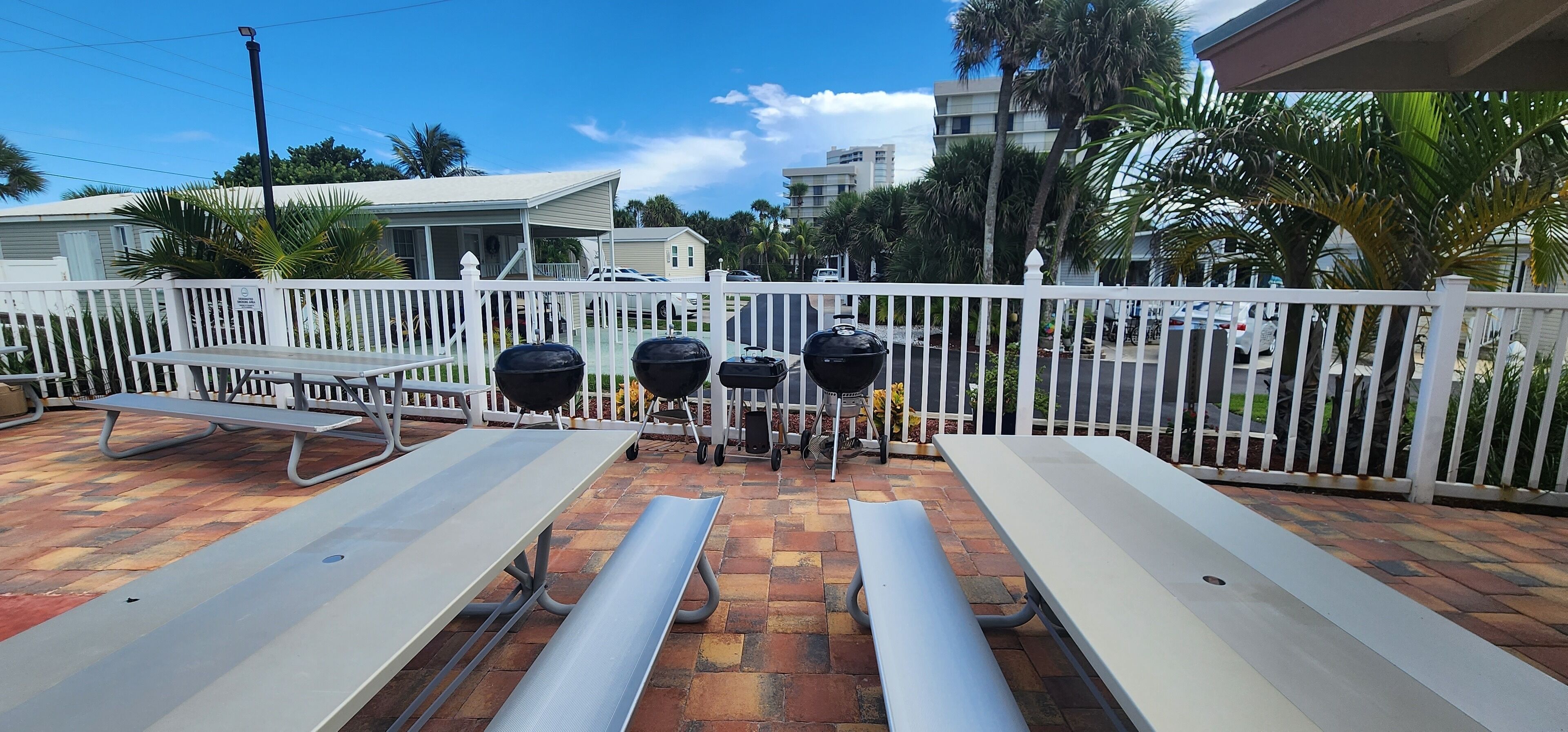 An outdoor patio with picnic tables and barbecue grills.