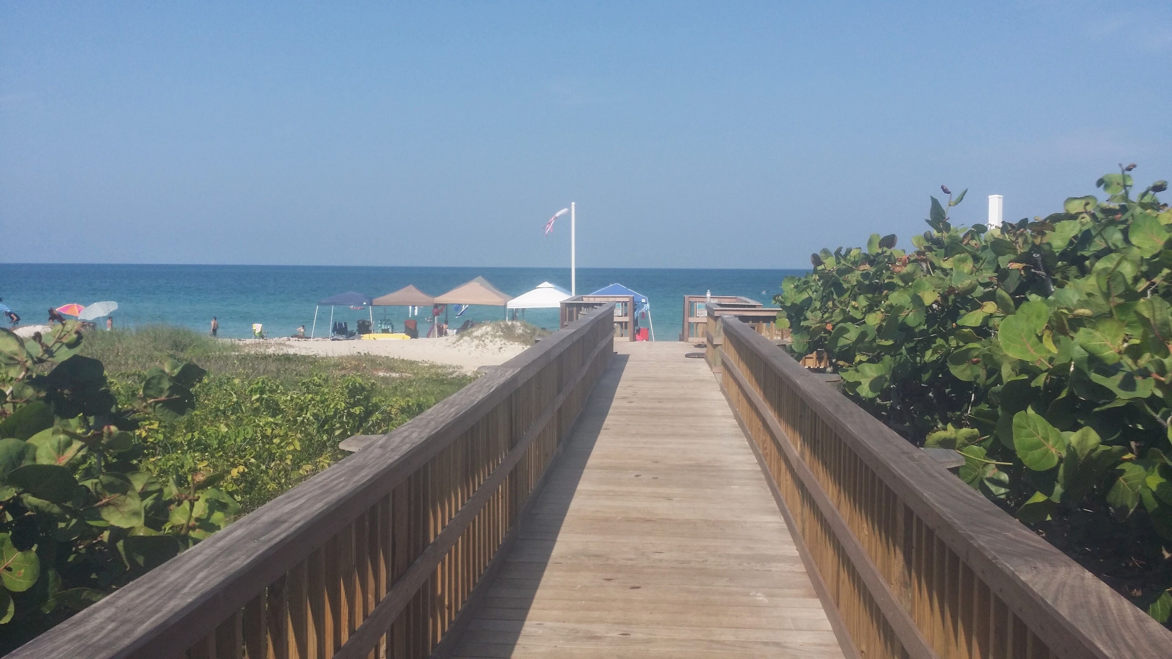 Una pasarela de madera que conduce a una playa con sombrillas y sillas.