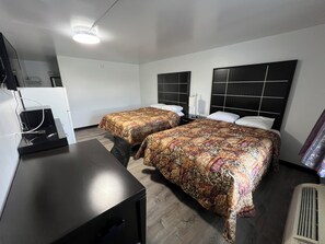A hotel room with two beds, a desk, and a television.
