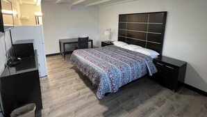 Ein Hotelzimmer mit Bett, Schreibtisch, Stuhl, Fernseher und Nachttisch.