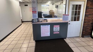 Ein Check-in-Empfangsbereich mit einem Schild, das die Check-in-Zeiten anzeigt, und einem Hinweis, dass für wöchentliche Tarife keine Rückerstattung erfolgt.