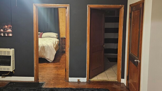 Ein Zimmer mit einem schwarzen Teppich, einem Deckenventilator, einem Bett mit weißer Bettdecke und einer Holztür.