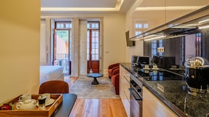 Habitación de hotel compacta con kitchenette, una cama, zona de comedor y vistas al exterior.