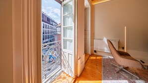 Quarto com uma janela grande, uma cadeira e um radiador.