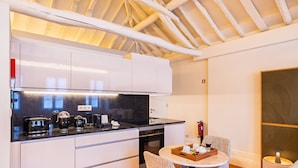 Una cocina moderna con armarios blancos, una encimera negra y una mesa de comedor redonda con una silla.