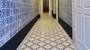 Un pasillo con baldosas estampadas en las paredes y el suelo, que conduce a una puerta al final.