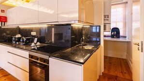 Una cocina moderna con encimera negra, electrodomésticos de acero inoxidable y ventana con vistas.