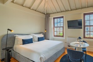 A bedroom with a bed, bedside lamp, TV, and a small table with a chair. - Intimate Studio near Bolhao Market (Oporto)