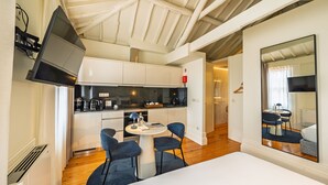 A modern kitchen with white cabinets, a black countertop, and a dining area with a round table and two chairs.