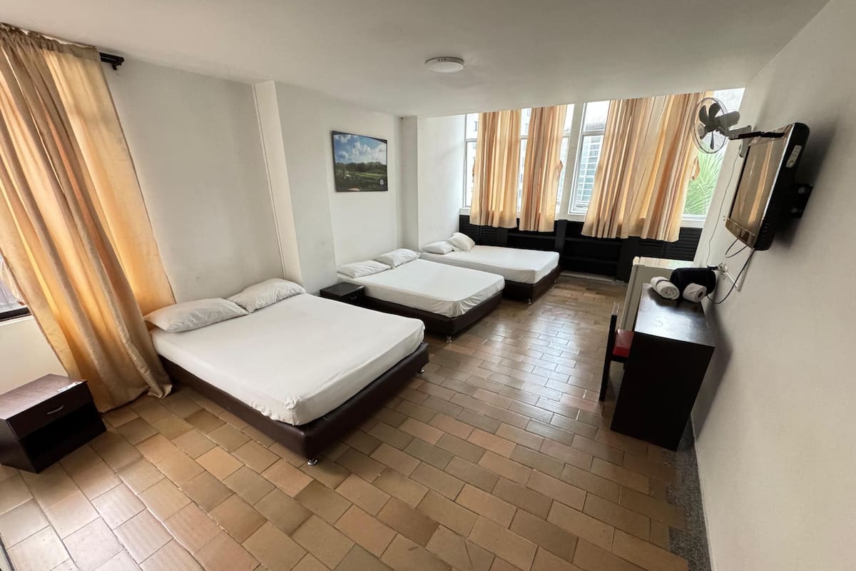 Een hotelkamer met twee bedden, een bureau, een televisie en een raam met gordijnen.