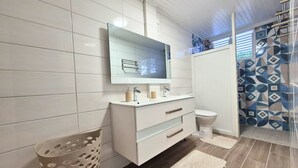 Een moderne badkamer met een wit wastafelmeubel, een spiegel, een toilet en een douchehoek.