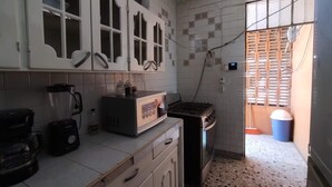 Een keuken met witte kastjes, een blender, een magnetron en een fornuis.