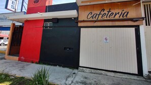 Een gebouw met een bord waarop 'cafeteria' staat, een gevel in rood en zwart, en een gesloten metalen poort.