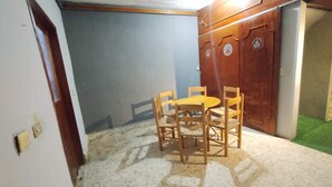 Een eethoek met een ronde tafel en vier stoelen, een houten garderobe met decoratieve panelen, en een vloerbedekking in het groen.