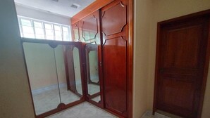 Een kamer met een betegelde vloer, een houten deur en een grote spiegel met houten lijst.