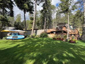 Een chalet met terras en boot in de voortuin.