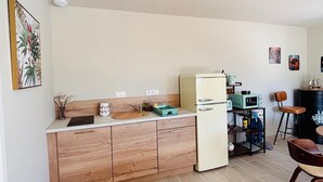 Eine kleine Küche mit Holzausstattung, einem Kühlschrank, einer Mikrowelle und einem Barhocker.