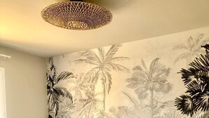 Ein Schlafzimmer mit einem Bett, einem Nachttisch und einer Wandmalerei mit tropischen Pflanzen.