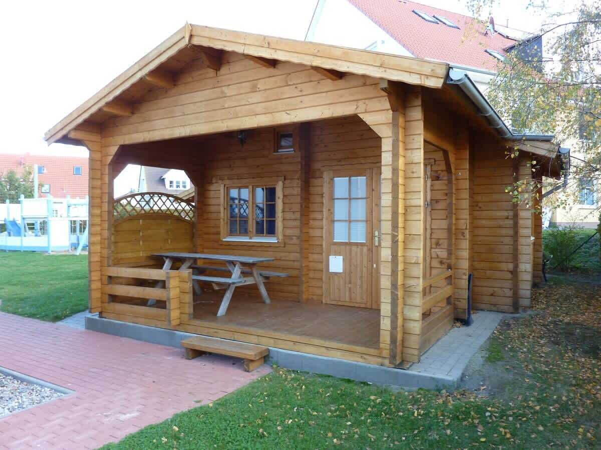 A wooden cabin with a picnic table and a door.