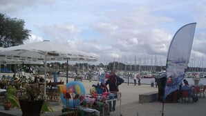 Un port de plaisance avec des bateaux, un espace abrité avec des tables et des chaises, et un stand de vente.