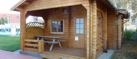 A wooden cabin with a picnic table and a door.