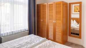 Ein Schlafzimmer mit einem Bett, einem Holzschrank und einem Fenster mit Vorhängen.