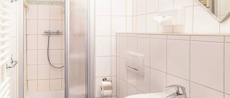 Une salle de bain avec une douche à parois de verre, un lavabo blanc et un miroir au-dessus du lavabo.