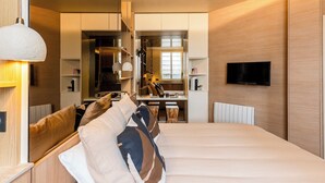 Une chambre d’hôtel moderne, dotée d’un grand lit, d’un bureau et d’une télévision.