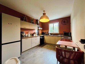 A compact kitchen with a dining area, featuring a microwave, toaster, and sink.