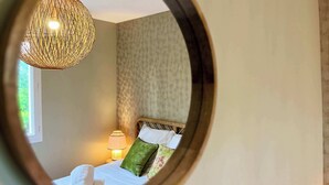Una camera da letto con un letto, cuscini, una lampada e un lampadario intrecciato.