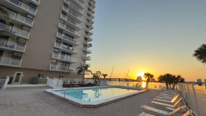 A swimming pool with a sunken deck, surrounded by lounge chairs, and a high-rise building with balconies. - Charming 1-bedroom apartment with WiFi, AC in fabulous Fort Myers Beach. (Fort Myers Beach)