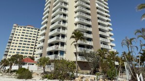 A high-rise hotel with multiple balconies, located near a sandy beach with palm trees. - Charming 1-bedroom apartment with WiFi, AC in fabulous Fort Myers Beach. (Fort Myers Beach)