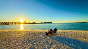 A beach with a sunset, a pier, and buildings in the background. - Charming 1-bedroom apartment with WiFi, AC in fabulous Fort Myers Beach. (Fort Myers Beach)