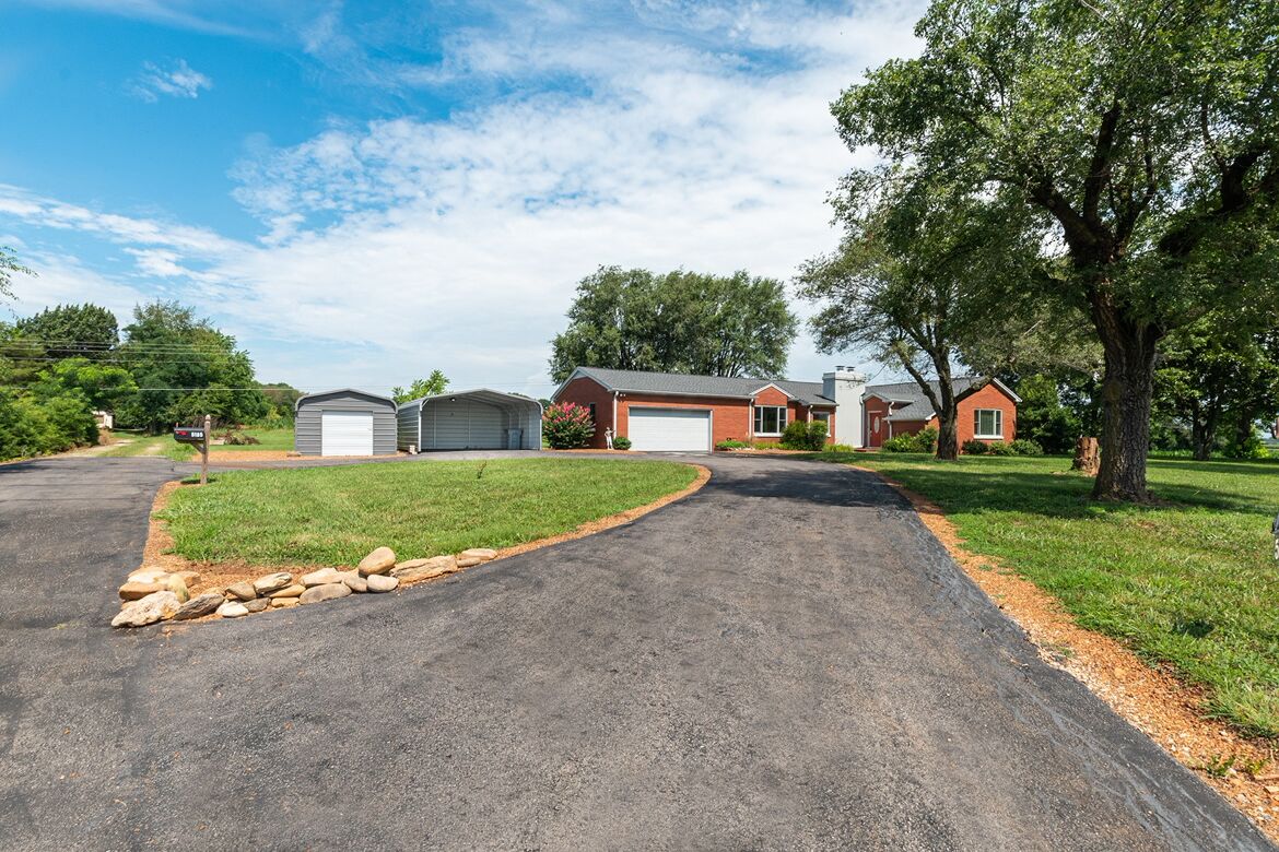 A residential driveway leading to a house with a garage, a covered porch, and a well-maintained lawn.