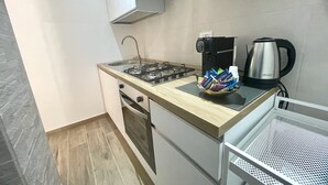 Una cocina compacta con estufa a gas, cafetera y hervidor.