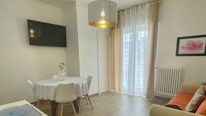 Una sala de estar moderna con comedor, un televisor de pantalla plana montado en la pared, una lámpara de techo y un radiador.