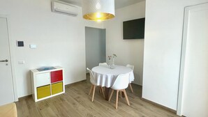 Una habitación moderna con una mesa de comedor, sillas, un armario blanco y una lámpara colgante.