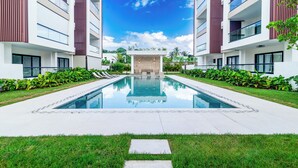 A modern hotel with a central pool, surrounded by lush greenery and two-story buildings with balconies. - Prado Suites Las Terrenas (Las Terrenas)