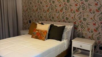 Ein Schlafzimmer mit einem Bett, einem Nachttisch, einer Hängelampe und einer Klimaanlage.