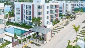A modern apartment complex with a swimming pool, outdoor seating, and a view of the surrounding hills. - Prado Suites Las Terrenas (Las Terrenas)